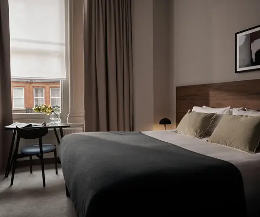 a bed with a black blanket and a chair in a room