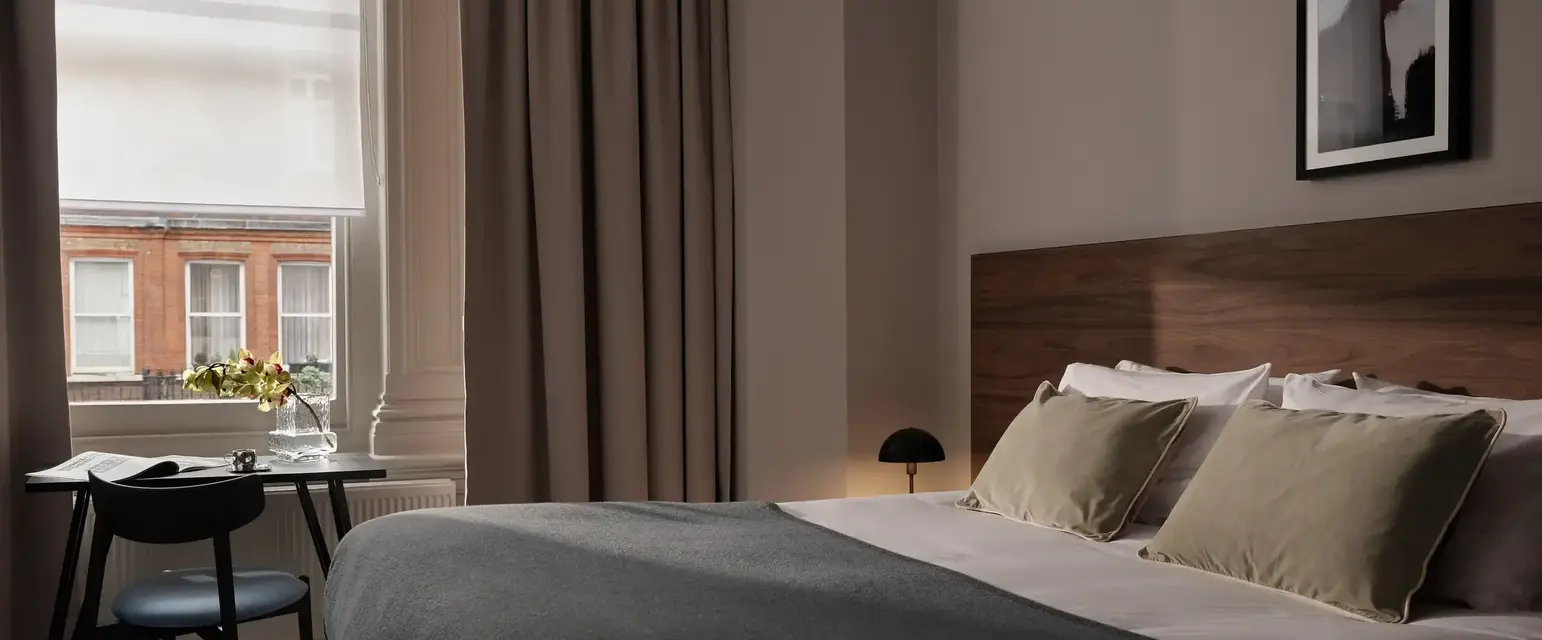 a bed with a black blanket and a chair in a room