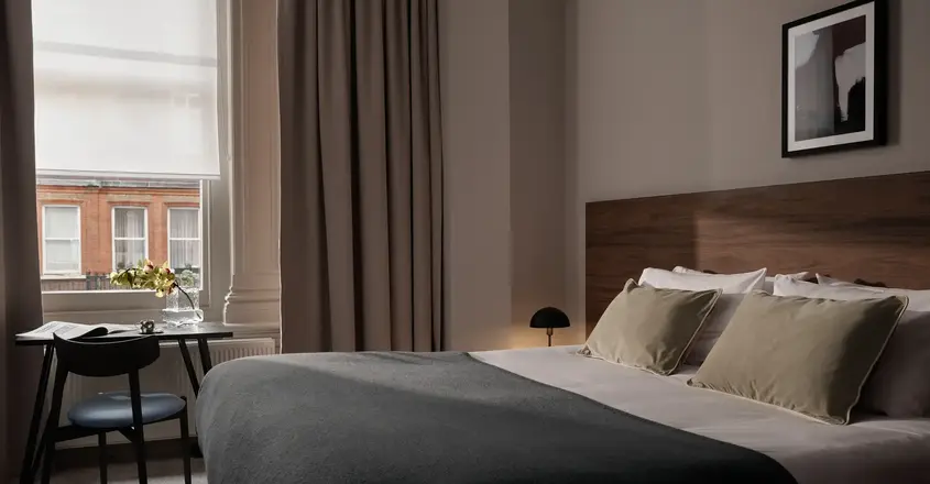 a bed with a black blanket and a chair in a room