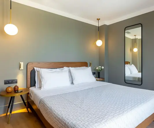 a bed with white sheets and a mirror in a room