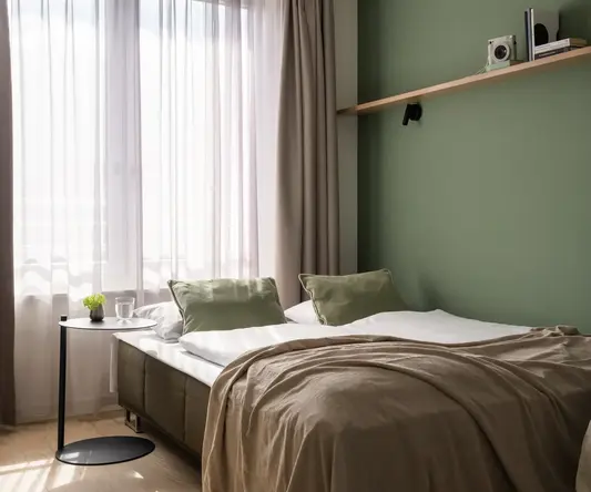 a bed with a green wall and a shelf