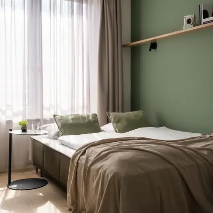 a bed with a green wall and a shelf