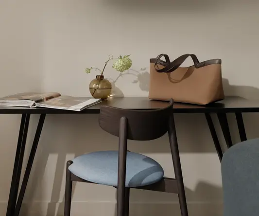 a chair and a table with a vase of flowers and a purse