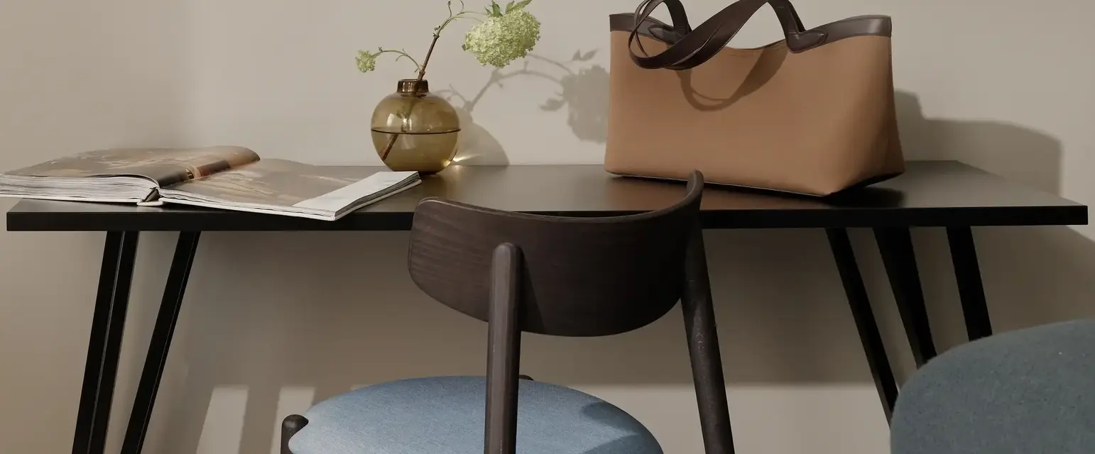 a chair and a table with a vase of flowers and a purse