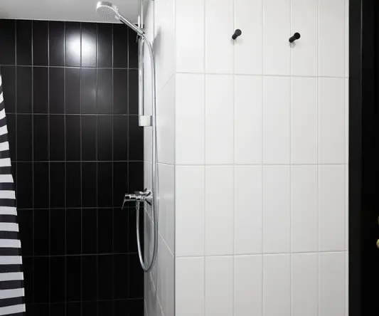a shower with a shower head and a black and white shower curtain
