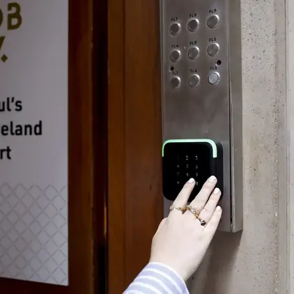 a person pressing a keypad on a metal panel