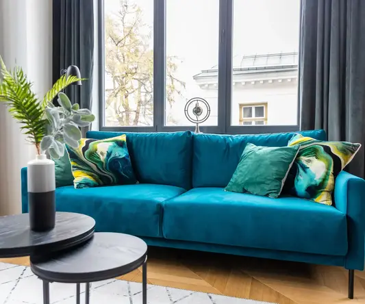 a blue couch with pillows in a room with windows