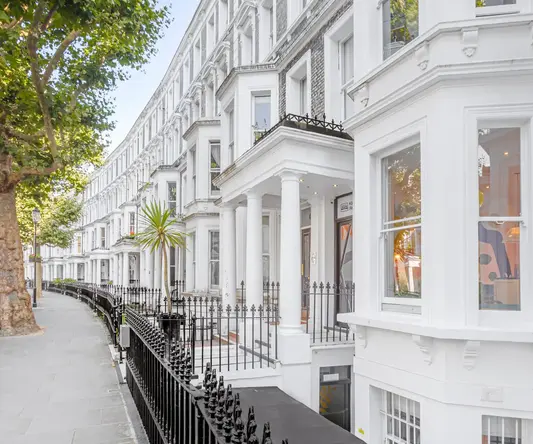 a white building with columns and a black fence
