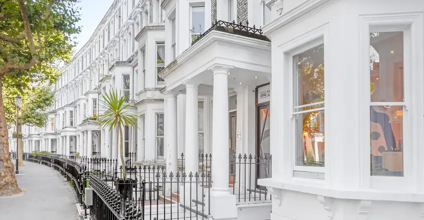 a white building with columns and a black fence