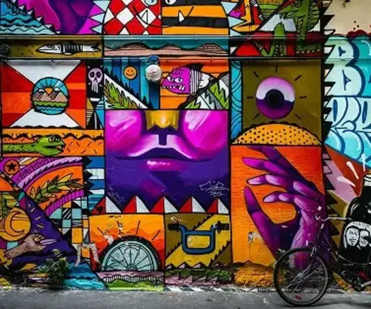 a bicycle parked next to a wall with colorful art