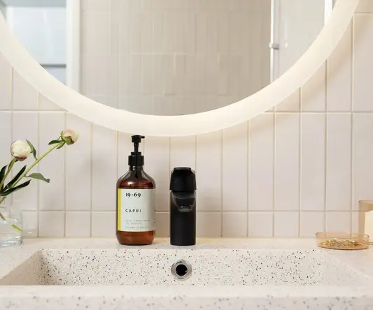 a bathroom sink with a mirror and a bottle of soap