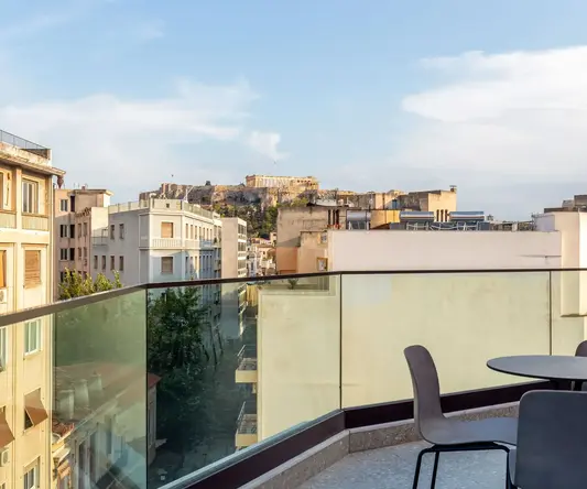 a balcony with chairs and a table and a glass railing
