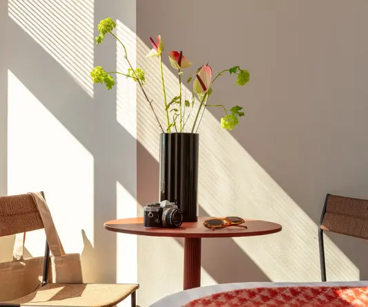 a vase with flowers and sunglasses on a table