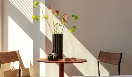 a vase with flowers and sunglasses on a table