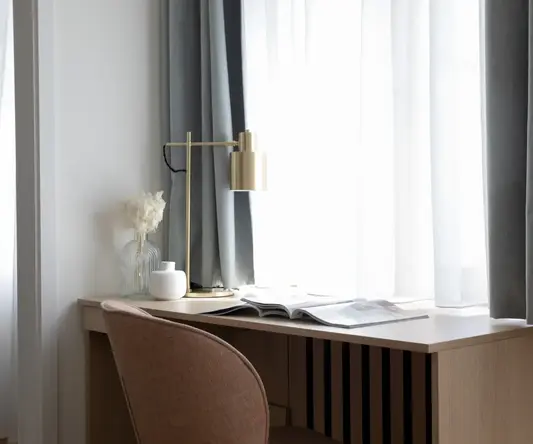 a desk with a lamp and a flower on it