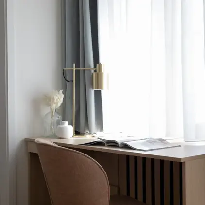 a desk with a lamp and a flower on it