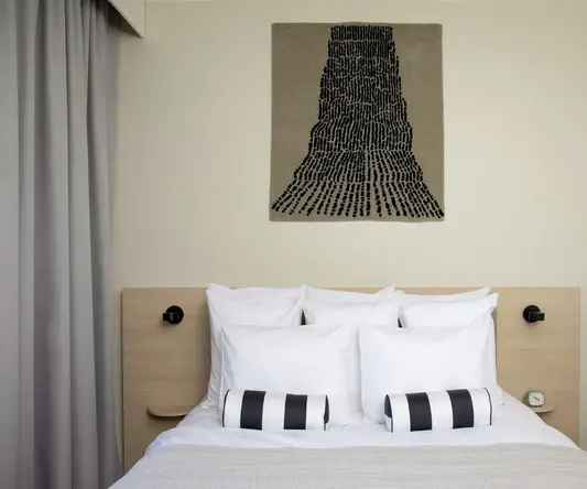 a bed with pillows and a piece of art above it