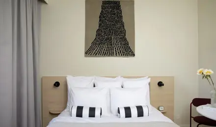 a bed with pillows and a piece of art above it