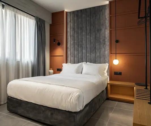 a bed with a lamp and a wall behind it