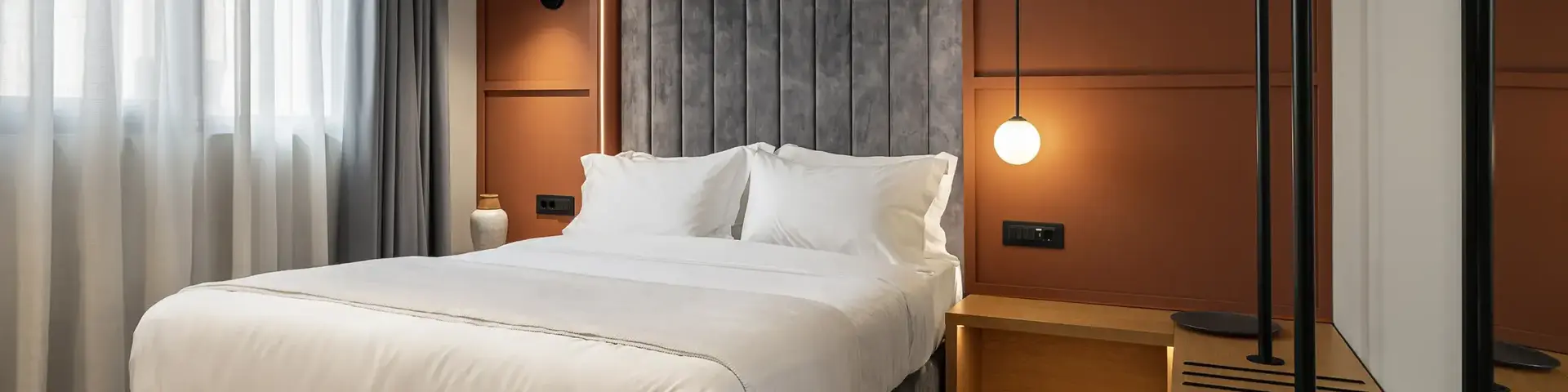 a bed with a lamp and a wall behind it