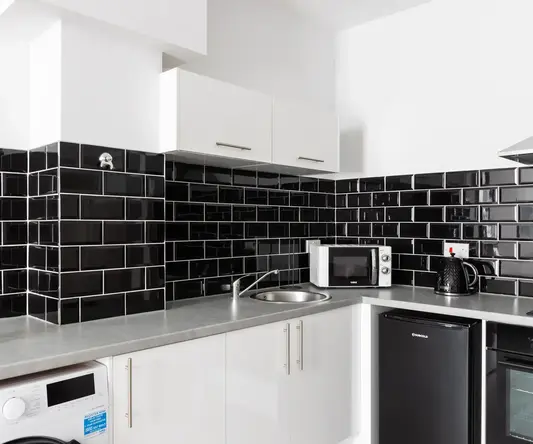 a kitchen with black tile walls and white cabinets