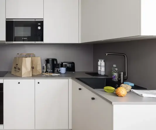 a kitchen with white cabinets and brown bags on top of it