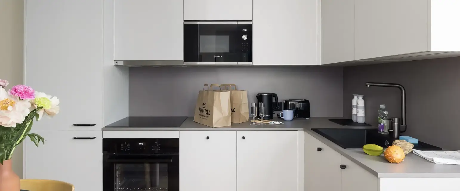 a kitchen with white cabinets and brown bags on top of it