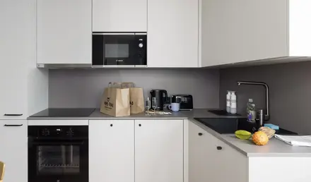 a kitchen with white cabinets and brown bags on top of it