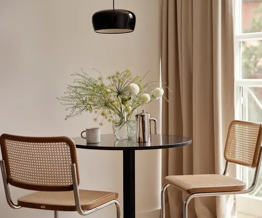 a table with chairs and a vase of flowers