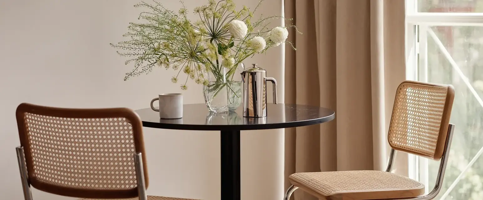 a table with chairs and a vase of flowers