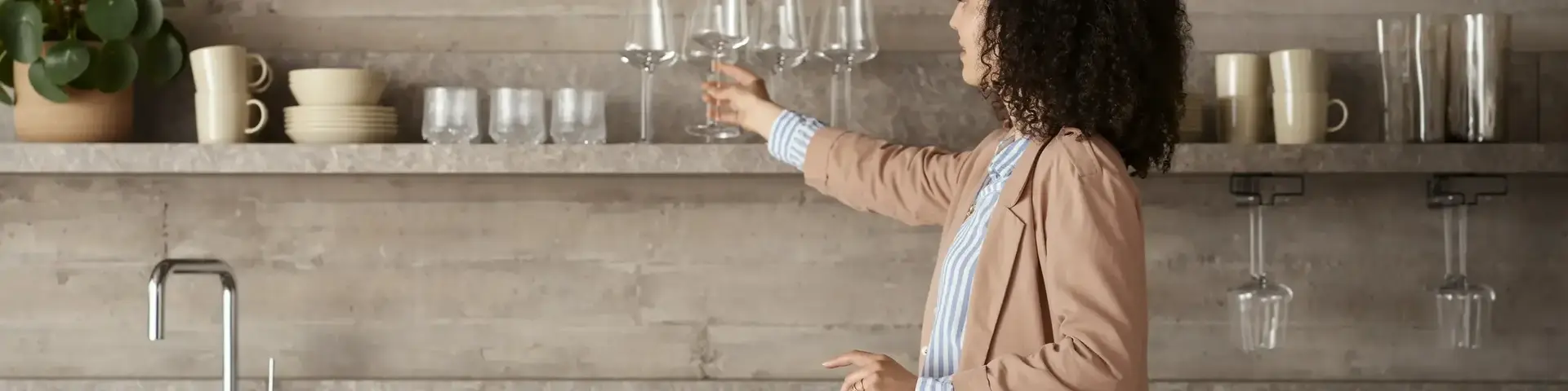 a woman holding wine glasses in a kitchen