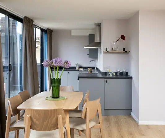 a dining table with chairs and a vase of flowers in a room