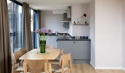 a dining table with chairs and a vase of flowers in a room