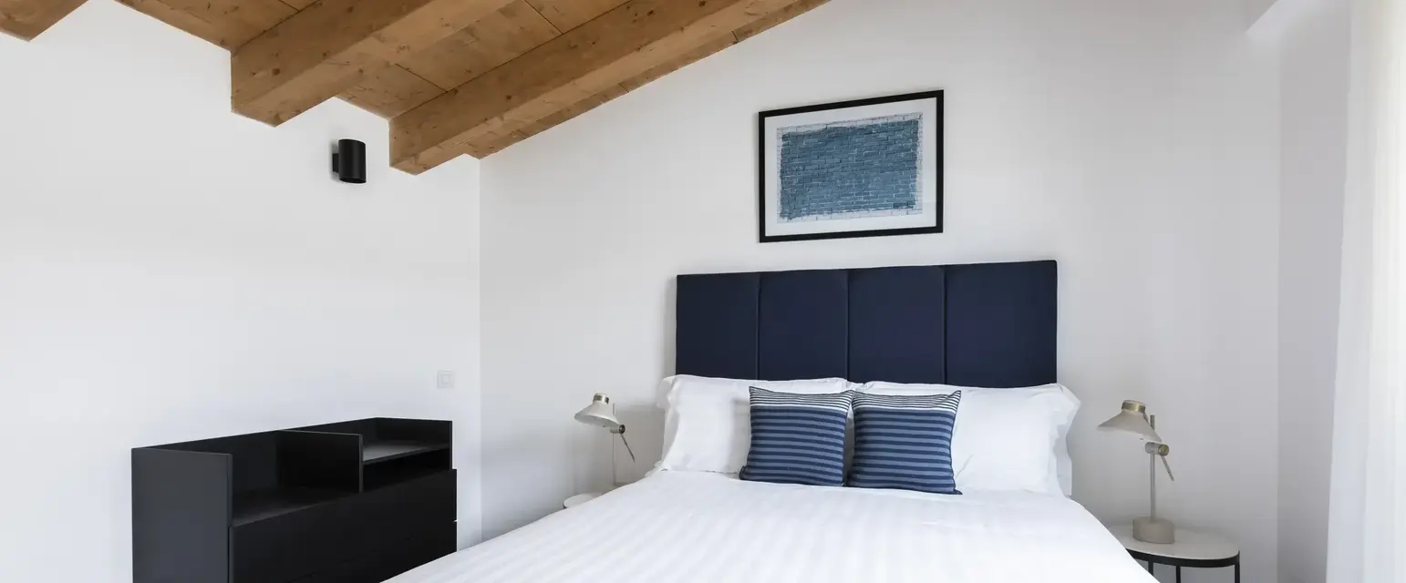 a bed with a blue headboard and a black shelf