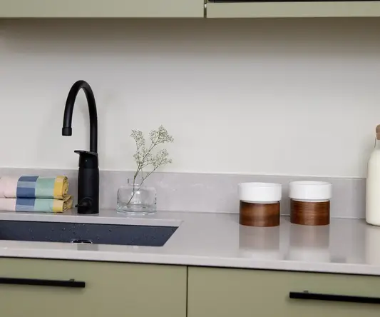 a kitchen counter with a microwave and a black faucet