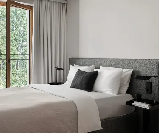 a bed with a black pillow and a table next to a window