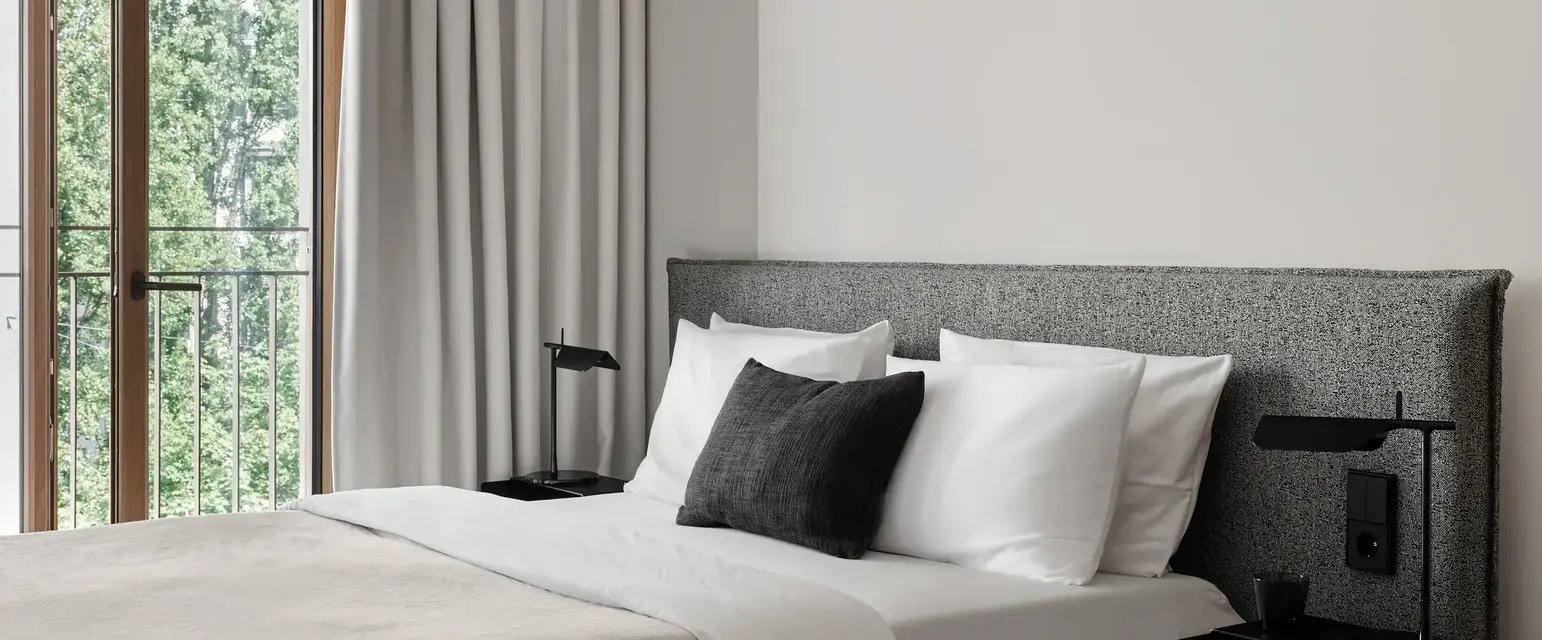 a bed with a black pillow and a table next to a window