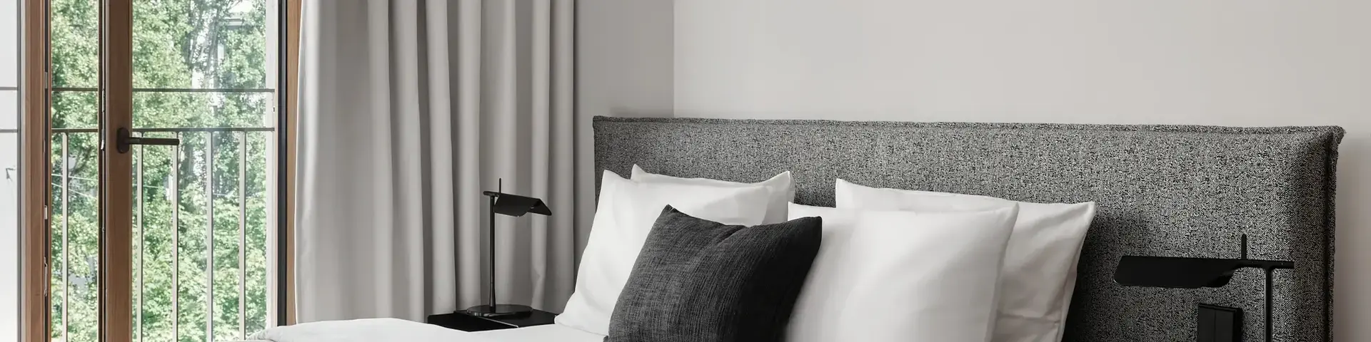 a bed with a black pillow and a table next to a window