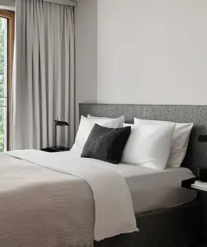 a bed with a black pillow and a table next to a window