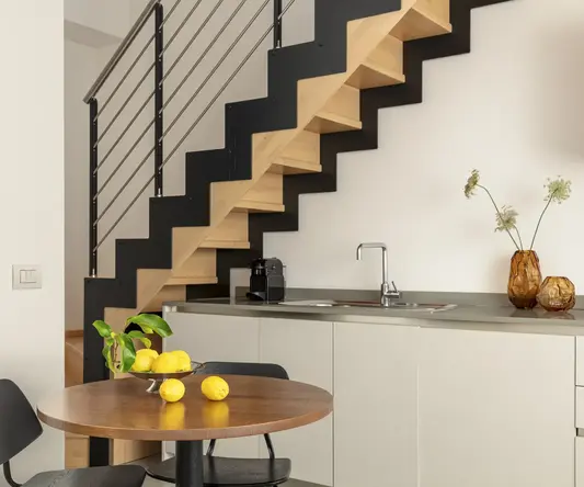 a kitchen with a staircase and a table with lemons