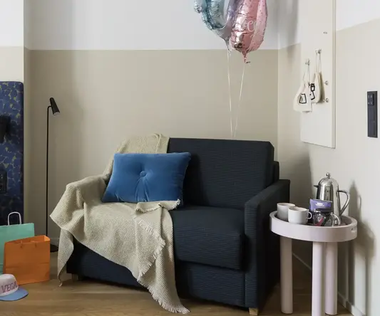 a couch with a blanket and balloons in a room
