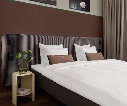 a bed with white sheets and brown striped headboard