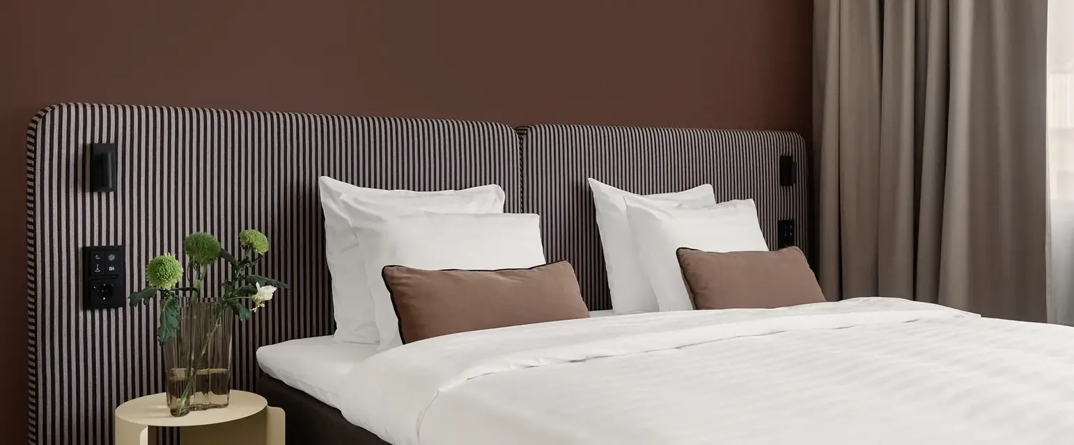 a bed with white sheets and brown striped headboard