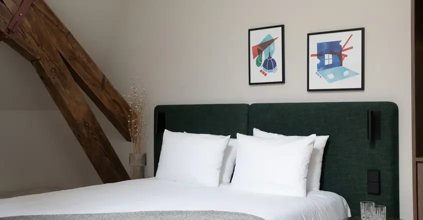 a bed with white pillows and a green headboard