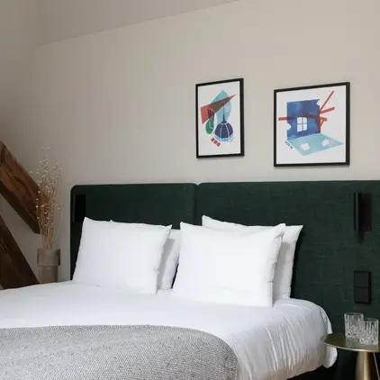a bed with white pillows and a green headboard