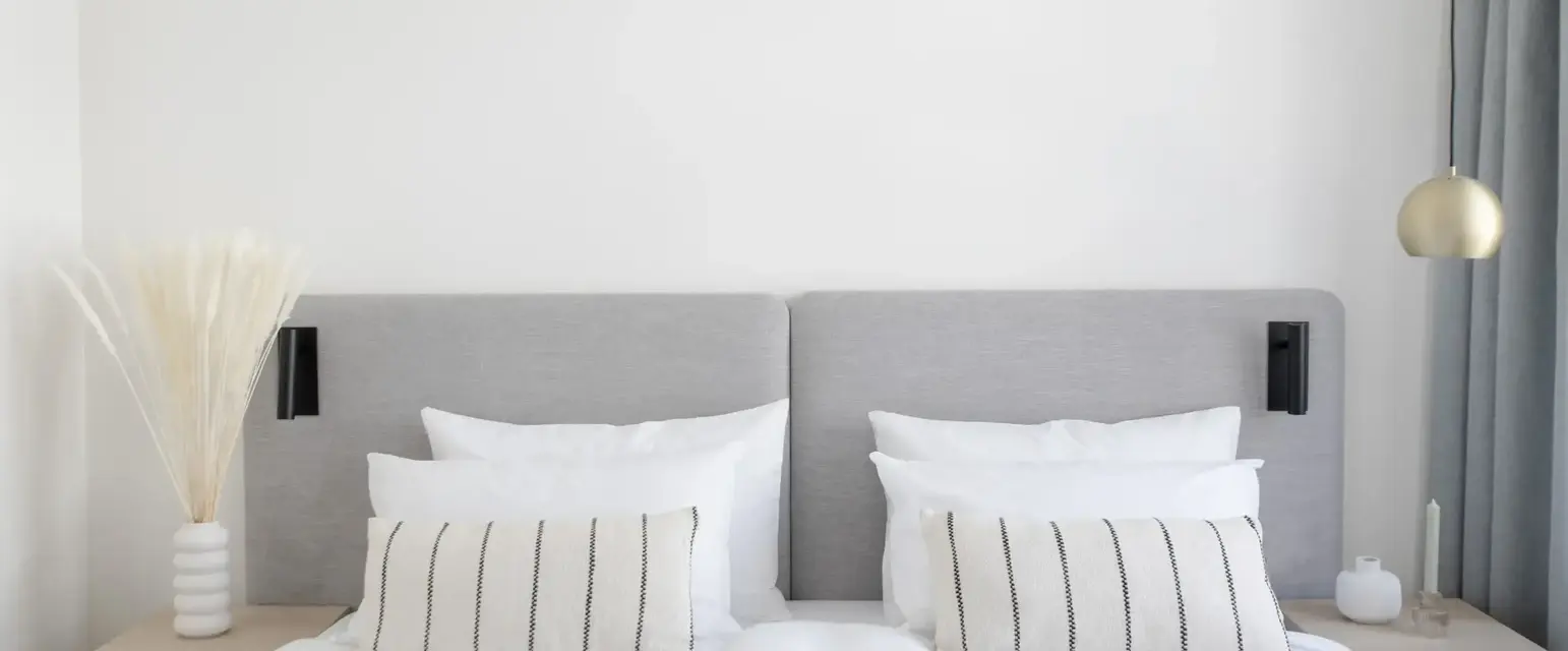 a bed with white sheets and pillows