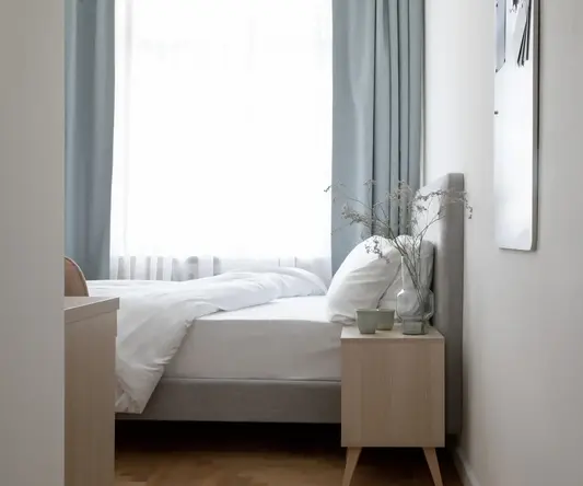 a bed with a vase of flowers on a nightstand