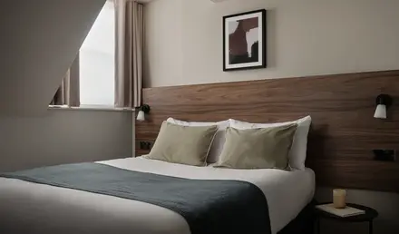 a bed with a wood headboard and a picture on the wall