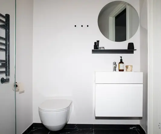 a bathroom with a round mirror and a toilet