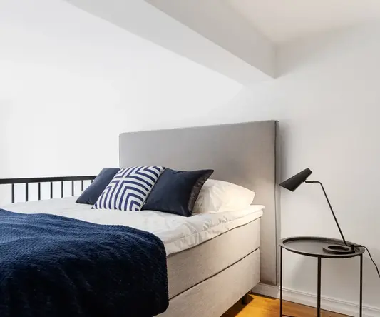 a bed with a blue blanket and a black lamp